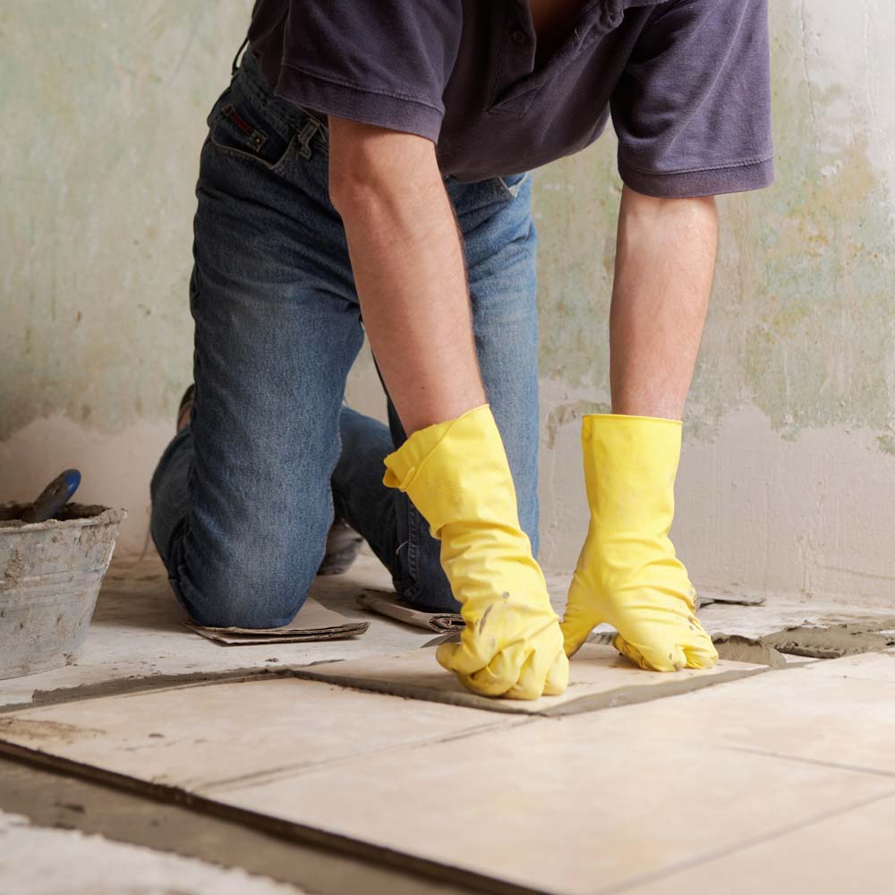 Man Fitting Tiles onto Flooring — GRT Building Supplies in Port Stephens, NSW